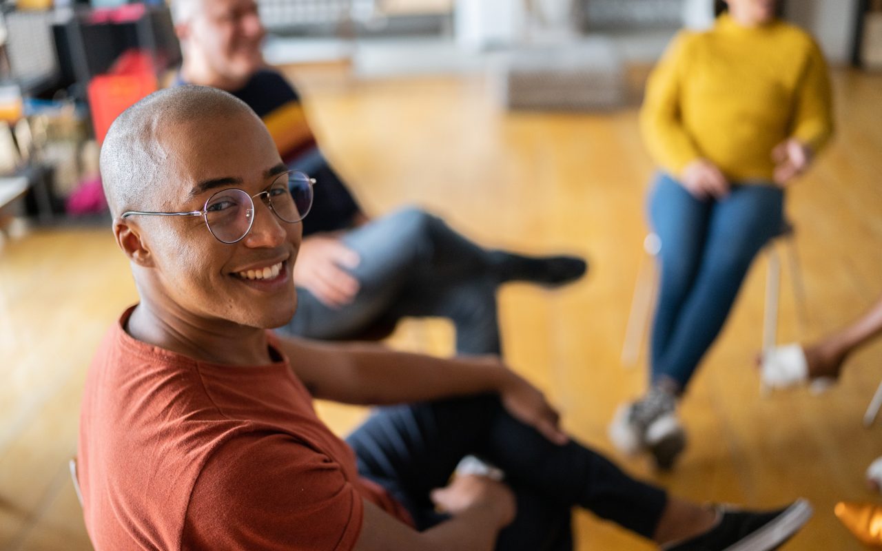 Portrait of a young man in group therapy at a coworking